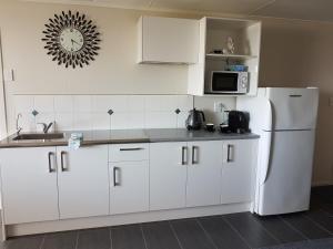
a kitchen with white cabinets and white appliances at Mike & Jenny's Kaka Point Accommodation in Kaka Point
