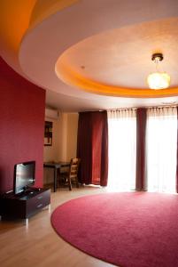 sala de estar con alfombra rosa y TV en Tsentralniy Hotel, en Khmelʼnytsʼkyy