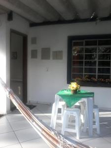 a table and two white stools with a green table at Suites do Reino Penedo RJ in Penedo