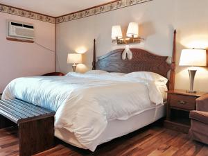 a bedroom with a large white bed and two lamps at Laurie's Inn in Chéticamp