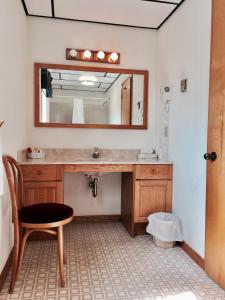 een badkamer met een wastafel, een spiegel en een stoel bij Laurie's Inn in Chéticamp