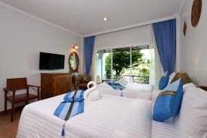 a bedroom with two beds and a tv and a window at Princess River Kwai Hotel in Kanchanaburi