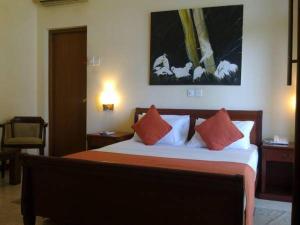 una camera da letto con un letto con cuscini arancioni e bianchi di Silvikris Villa a Colombo