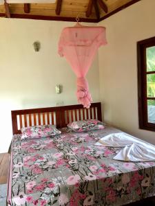a bedroom with a bed with a pink curtain on it at Seasons Four Mini Jungle Cabana in Matara