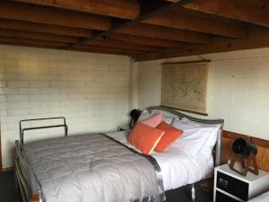 1 dormitorio con 1 cama con almohadas de color naranja y blanco en The Workshops Clyde, en Clyde
