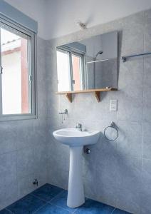 een badkamer met een witte wastafel en een spiegel bij La Posta de la Laguna in La Paloma