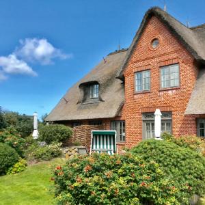 an old brick house with a thatched roof at Kleiner Ulenhof in Wenningstedt