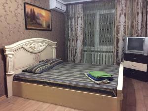 クルィヴィーイ・リーフにあるApartment on Ukrainskayaのベッドルーム(ベッド1台、テレビ、カーテン付)