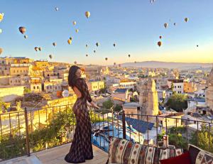 une femme debout sur un balcon donnant sur les montgolfières dans l'établissement Vista Cave Hotel, à Gorëme