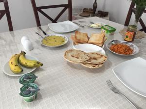 ヌワラエリヤにあるPerera Homestayの食べ物、バナナ、パンが並ぶテーブル
