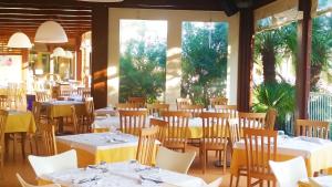 a restaurant with white tables and chairs and windows at Villaggio Centro Vacanze De Angelis in Numana