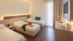 a hotel room with two beds and a television at Hotel Adria in Lignano Sabbiadoro