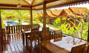un restaurant avec des tables et des chaises en bois sur une terrasse couverte dans l'établissement Thai House Resort, à Hua Hin