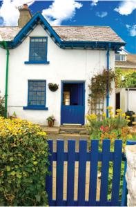 a blue fence in front of a white house at Slieve Donard Cottage in Newcastle