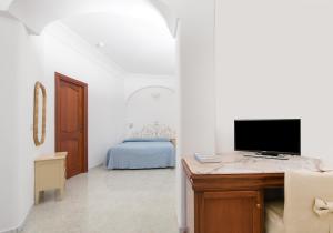 a bedroom with a bed and a desk with a television at Hotel Pupetto in Positano