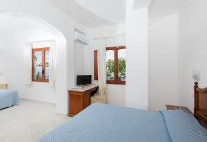 a bedroom with a bed and a desk with a computer at Hotel Pupetto in Positano