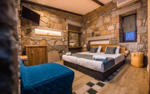 a bedroom with a bed and a stone wall at Keros Blue - Luxury in Wilderness in Kalliópi