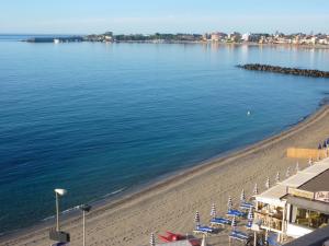 a beach with chairs and umbrellas next to the water at Hotel Palladio in Giardini Naxos