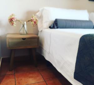 Una cama con una mesita con flores. en Alda Hospedería De Los Reyes, en Toledo