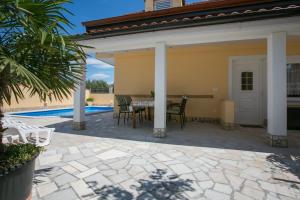 taras ze stołem i krzesłami obok basenu w obiekcie Holiday Home "Mala kuća " with heated pool w Puli