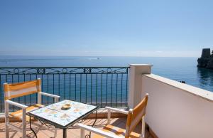 a balcony with two chairs and a table and the ocean at Hotel Pupetto in Positano