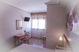 a bedroom with a bed and a desk and a window at L'Oncle Pere Habitacions in L'Alcúdia