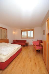 a bedroom with a bed and a couch and a table at Wellness Pension Waldhof in Sankt Georgen