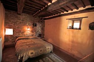 Un dormitorio con una cama y una pared de piedra. en Podere di Maggio - Casa Grande, en Santa Fiora