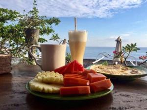 einen Obstteller auf dem Tisch mit einem Getränk in der Unterkunft Putra'Lebah Amed Guest House in Amed