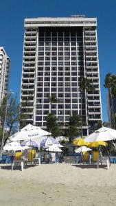 un gran edificio en la playa con sillas y sombrillas en Aconchegante Flat na Orla, en Recife