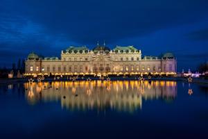 een groot gebouw met een reflectie in het water 's nachts bij Austria Center - Wien an der Donau in Wenen