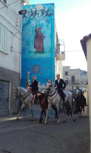 grupa ludzi jeżdżących konno po ulicy w obiekcie Orgosolo B&B Sardegna w mieście Orgosolo