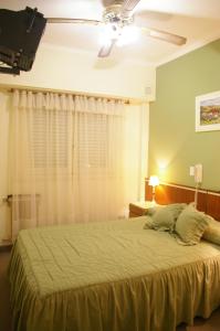 um quarto com uma cama grande e uma ventoinha de tecto em Hotel Compostela em Mar del Plata