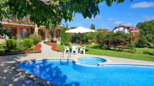 a swimming pool with a table and an umbrella at Family Hotel Vega in Saints Constantine and Helena