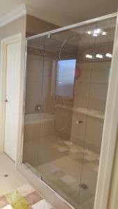 y baño con ducha y puerta de cristal. en Vimal's Homestay en Perth