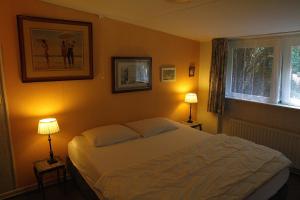 een slaapkamer met een wit bed en 2 lampen bij De Boem in Westermient