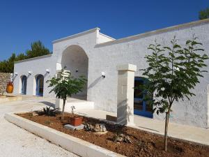a white building with two trees in front of it at Antica Masseria Torre Mozza in Torre Santa Susanna