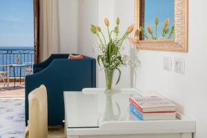 a vase of flowers on a table with a blue chair at Hotel Pupetto in Positano