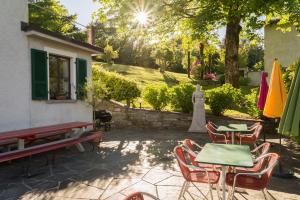 une terrasse avec des tables et des chaises en face d'une maison dans l'établissement Ostello & Camping Riposo, à Losone