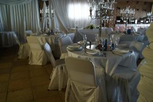 a dining room with white tables and chairs and chandeliers at Sea Otters Lodge in Kini Bay