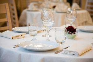 una mesa con platos blancos y vasos. en Hotel Ristorante Cesare, en Savignano sul Rubicone