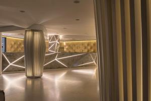 a lobby with a gold wall and a large light fixture at Hotel Oasi Di Kufra in Sabaudia