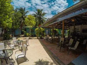 un patio con mesas, sillas y palmeras en Sea Gate Beach Resort, en Thong Sala