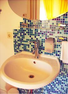 ein Badezimmer mit einem Waschbecken und einer blau gefliesten Wand in der Unterkunft Hotel Gasthaus Krone in Köln