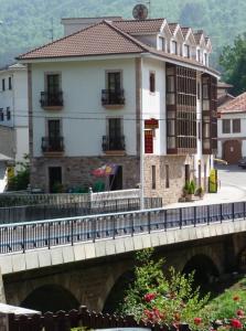 a bridge over a river with a building at Hostal Gogar in Puentenansa