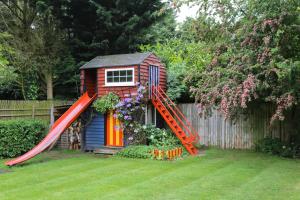 a small house with a red slide in a yard at Surlingham Lodge Cottages in Norwich
