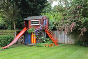 a small house with a red slide in a yard at Surlingham Lodge Studio Large Family Cottage in Norwich