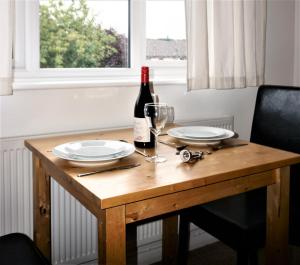 a wooden table with two plates and a bottle of wine at The Worthys in Bristol