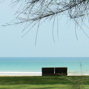 a bench sitting on the beach near the ocean at Costa Lanta - Adult Only in Ko Lanta