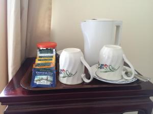 a table with two cups and a coffee maker on it at Fern Cottage in Dorchester
